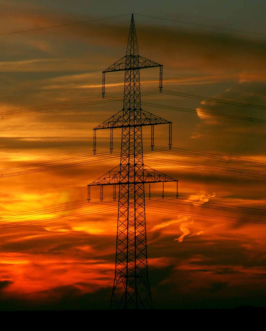 Ein Hochspannungsmast bei Sonnenaufgang.
